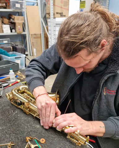 Leisure Coast Wind & Brass's Beginner Repair Tech Ollie working on a saxophone